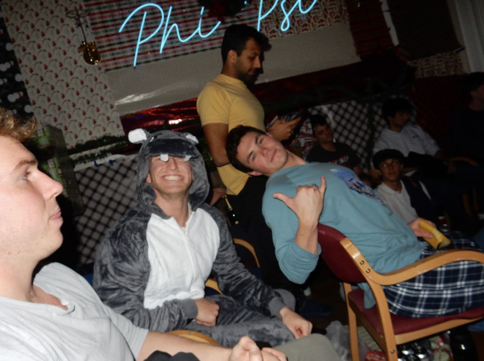 Brothers watching the roast beneath the Phi Psi neon sign.