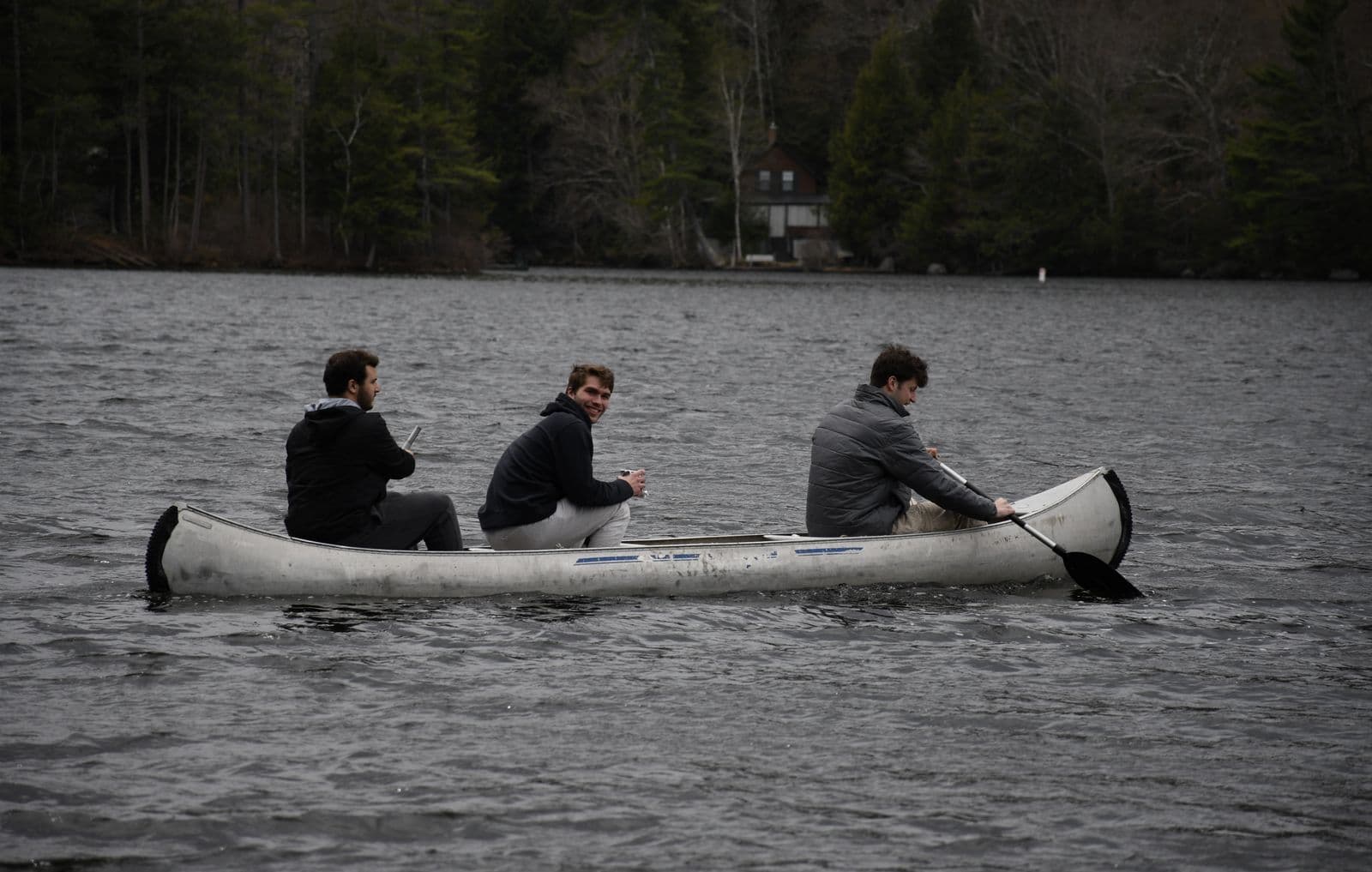 Three brothers paddling a canoe across the lake.