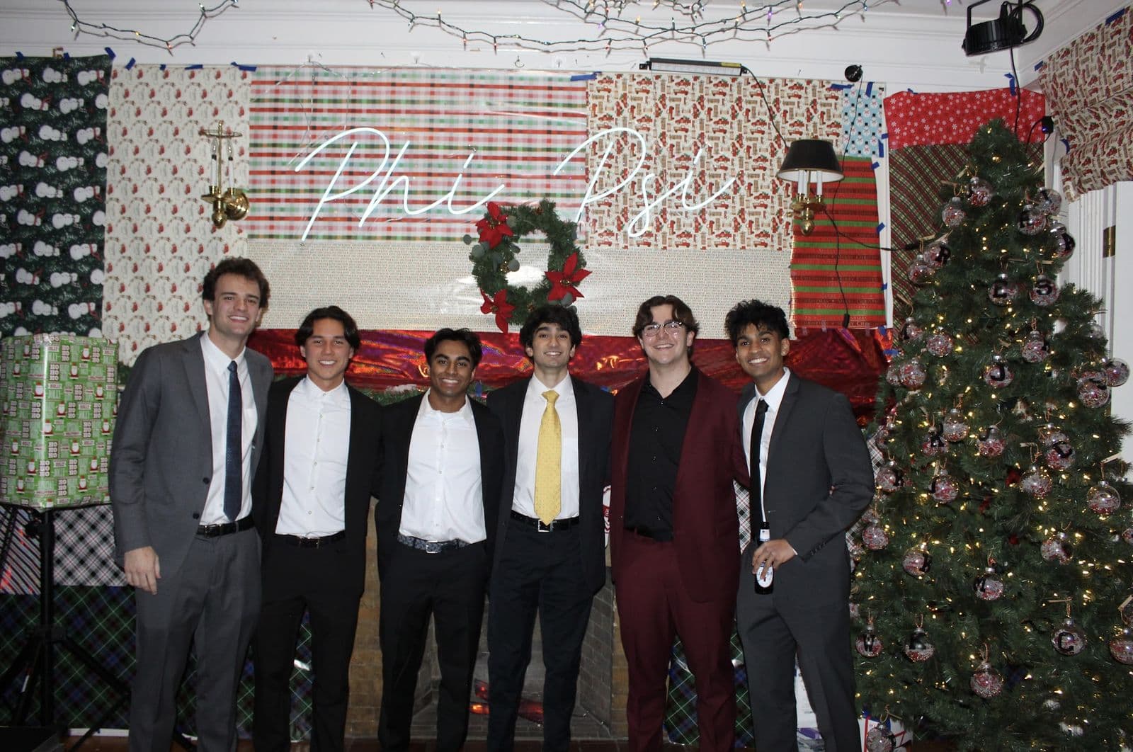 Brothers in suits at Fall Formal beside a decorated Christmas tree.