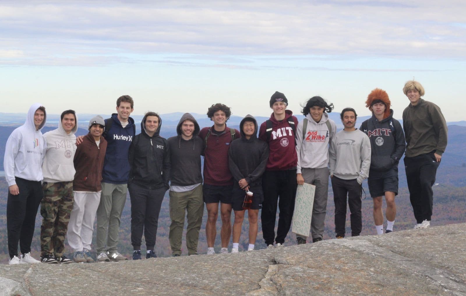 Brothers lined up on a granite summit with autumn hills behind them.