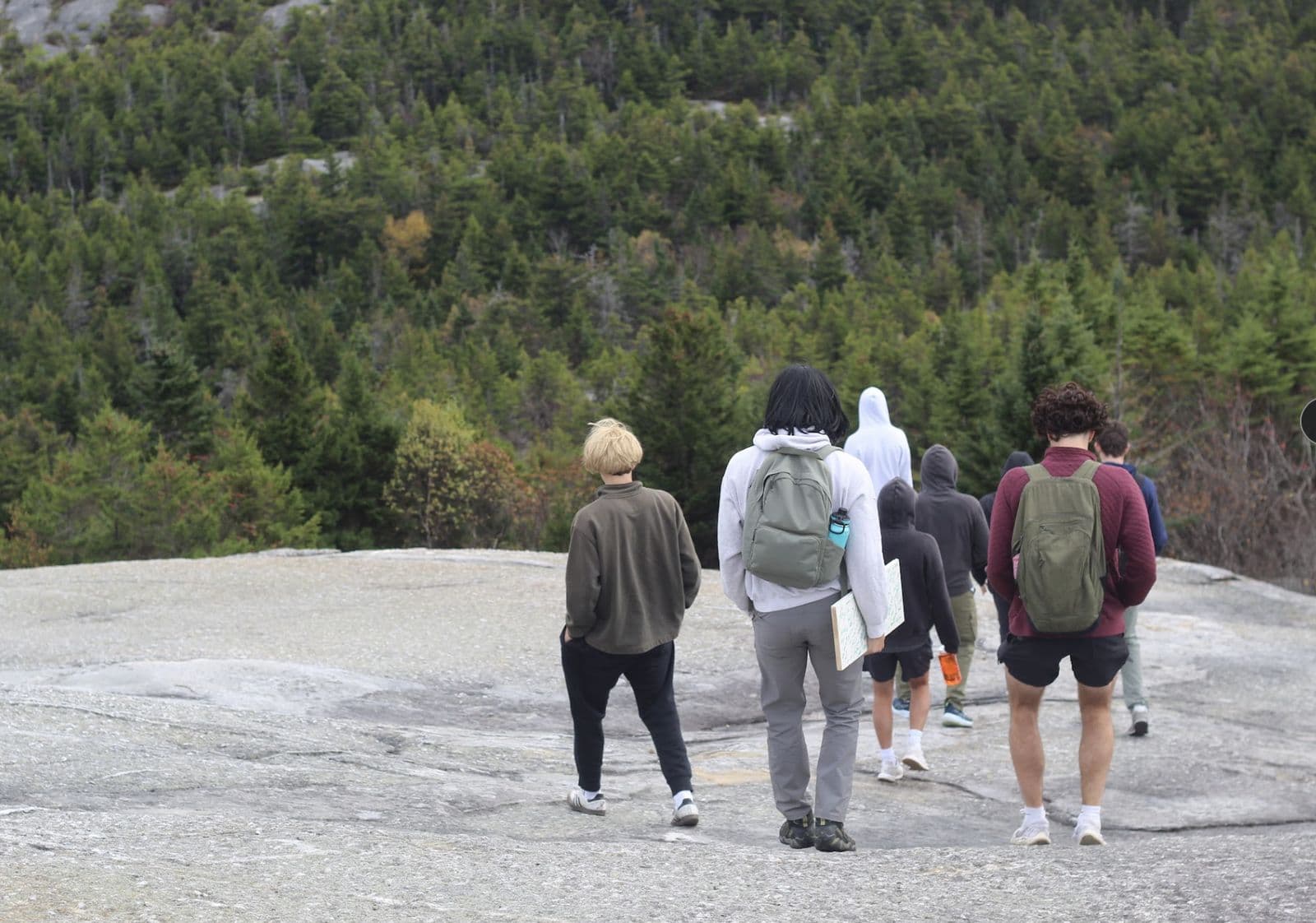 Hikers crossing an open granite ledge above the treeline.