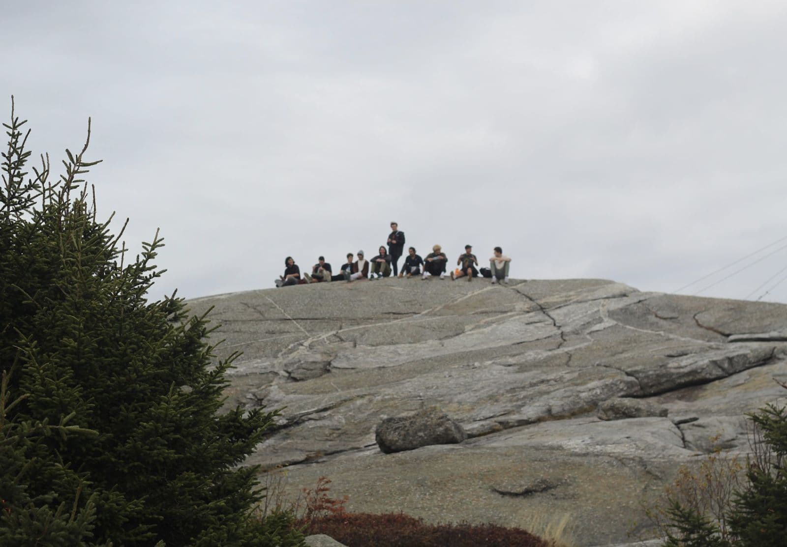 The group resting on a rocky outcrop, seen from across the ridge.