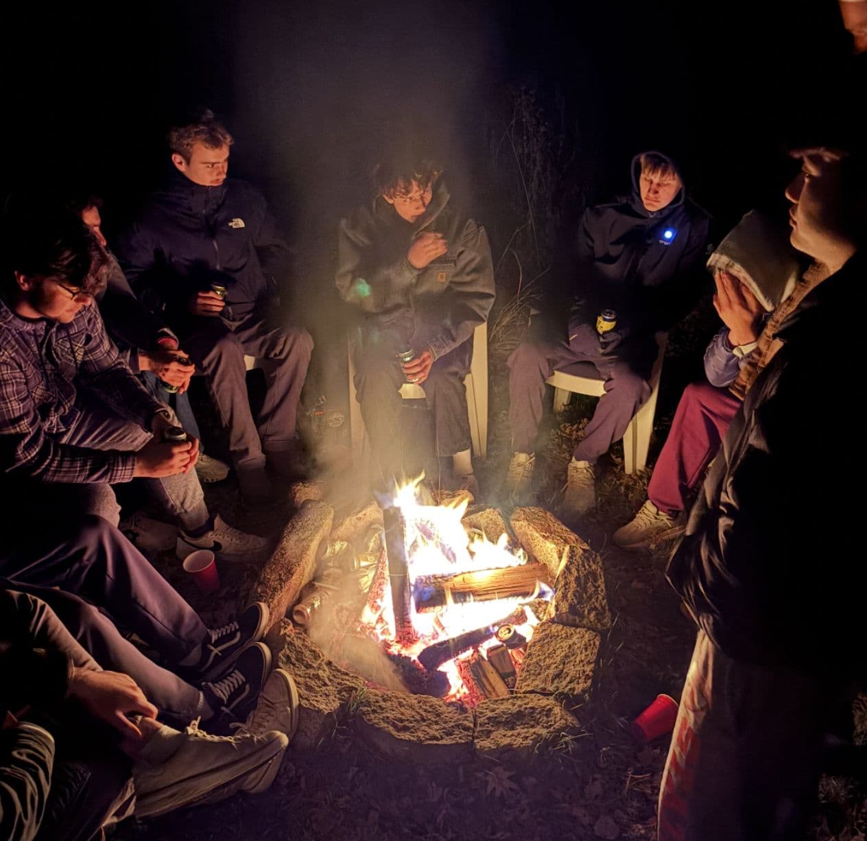 The pledge class gathered around a campfire after dark.