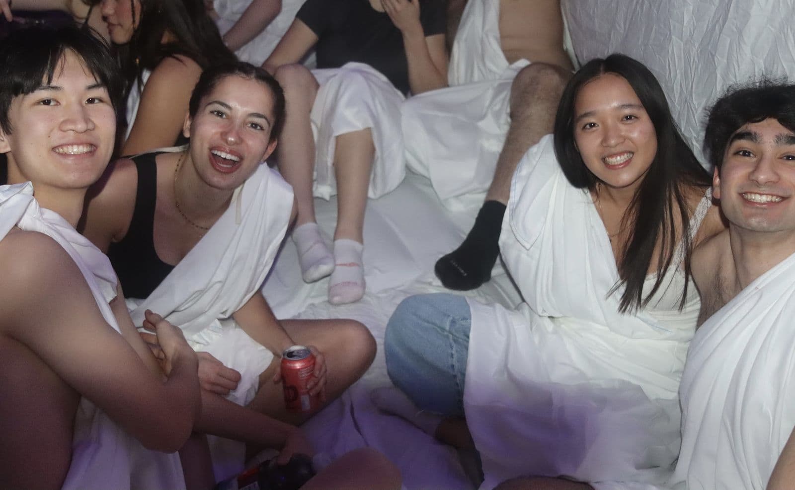 Brothers and guests in togas seated together at the party.