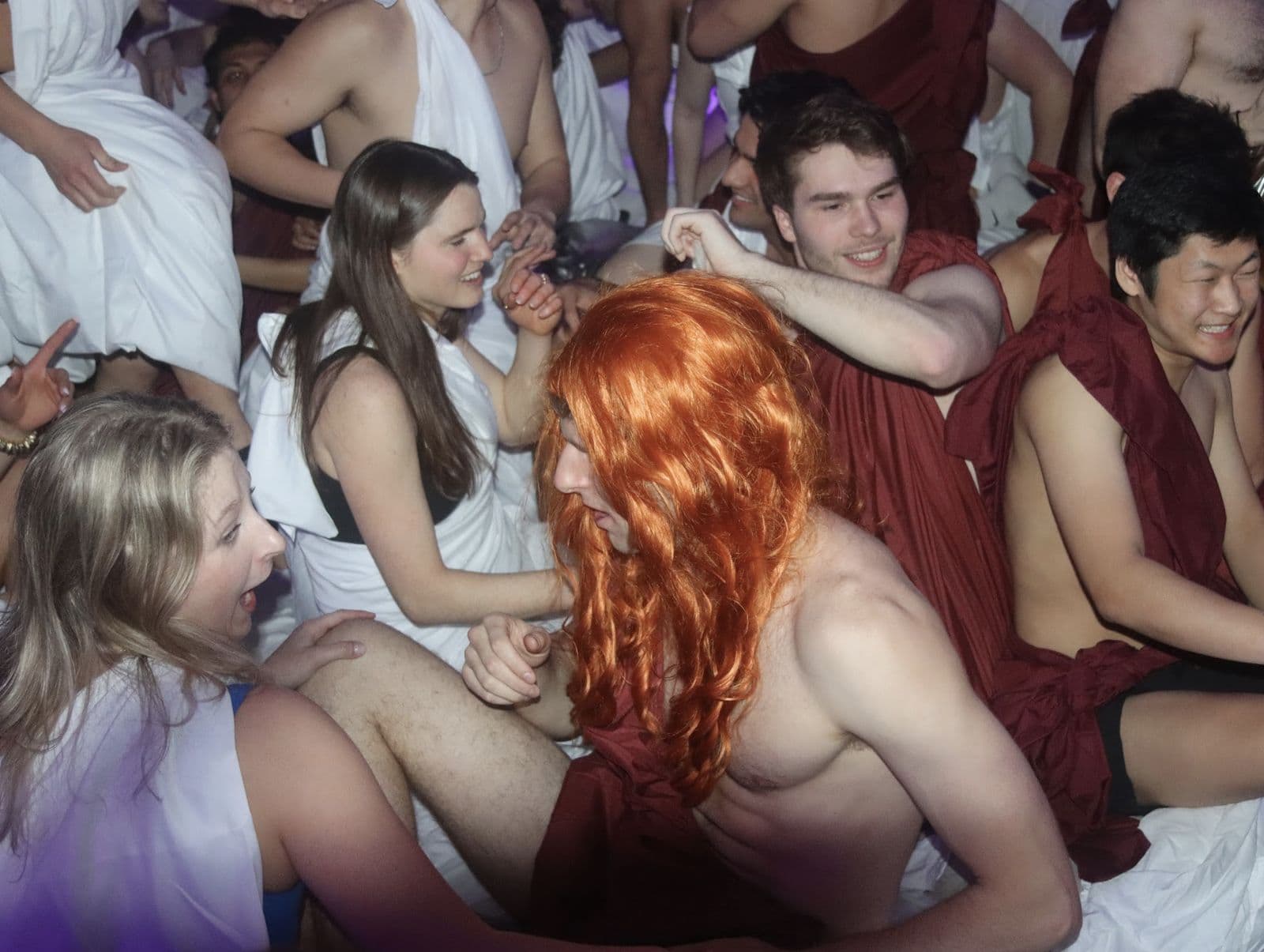 A packed room of guests in togas.