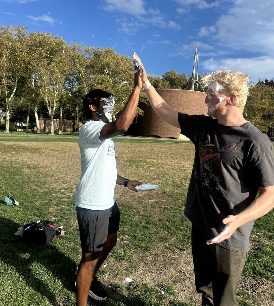 Two brothers high-fiving at an outdoor campus charity event.