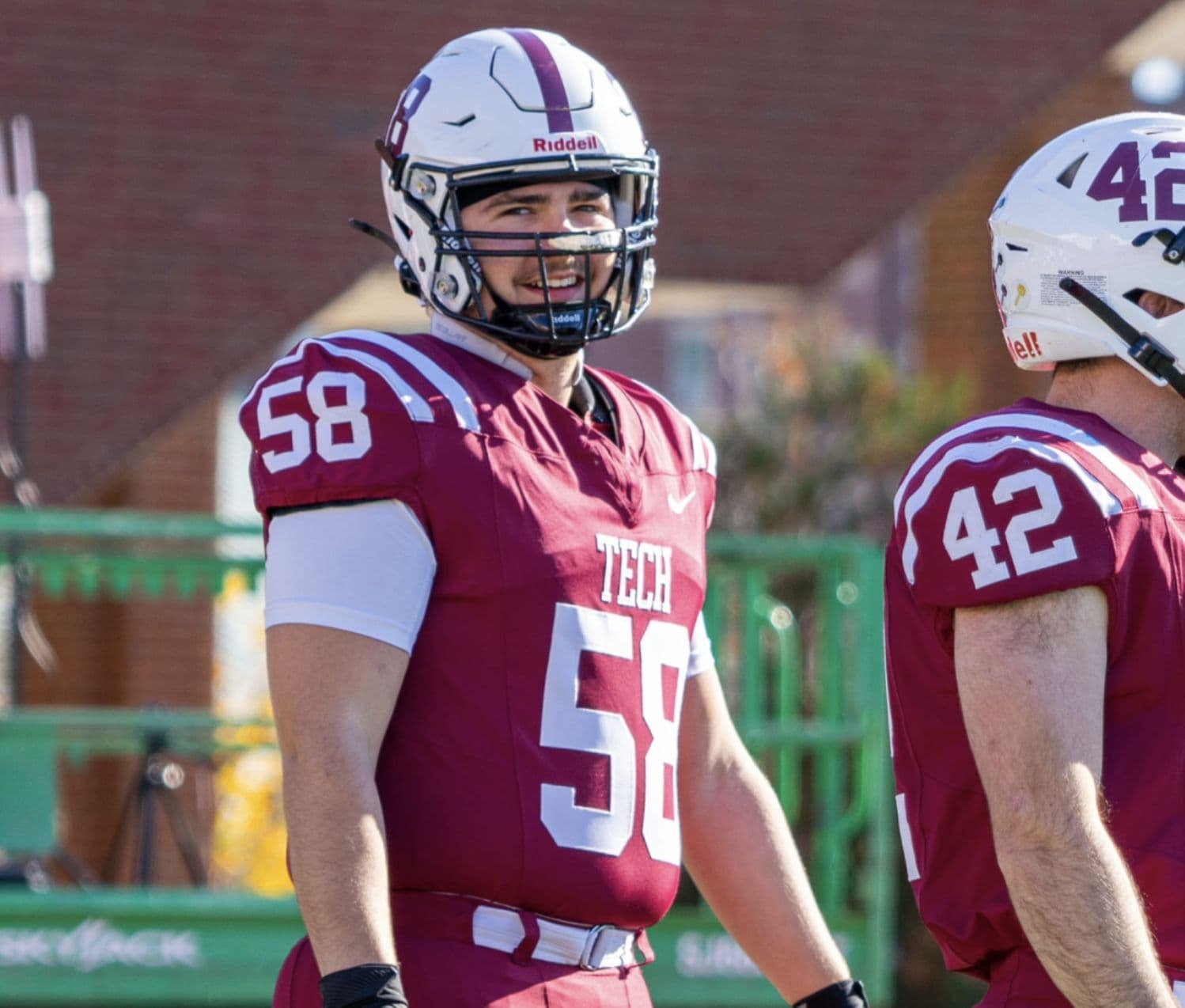 MIT football players in maroon TECH jerseys on the sideline.
